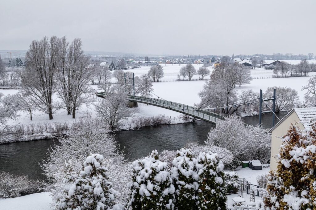 Blick von Weingartsgasse auf die Siegbrücke. Die Brücke und die dahinter liegenden Siegauen sind mit weißem Schnee bedeckt den noch niemand gestört hat.