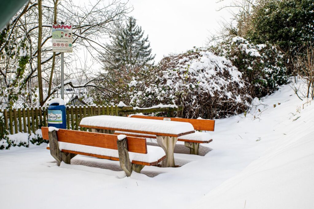 Der Spielplatz im Winter. Schnee liegt Zentimeterhoch auf den Bänken und Tischen.